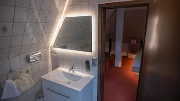 A modern bathroom with a white sink, mirror, and towel rack.