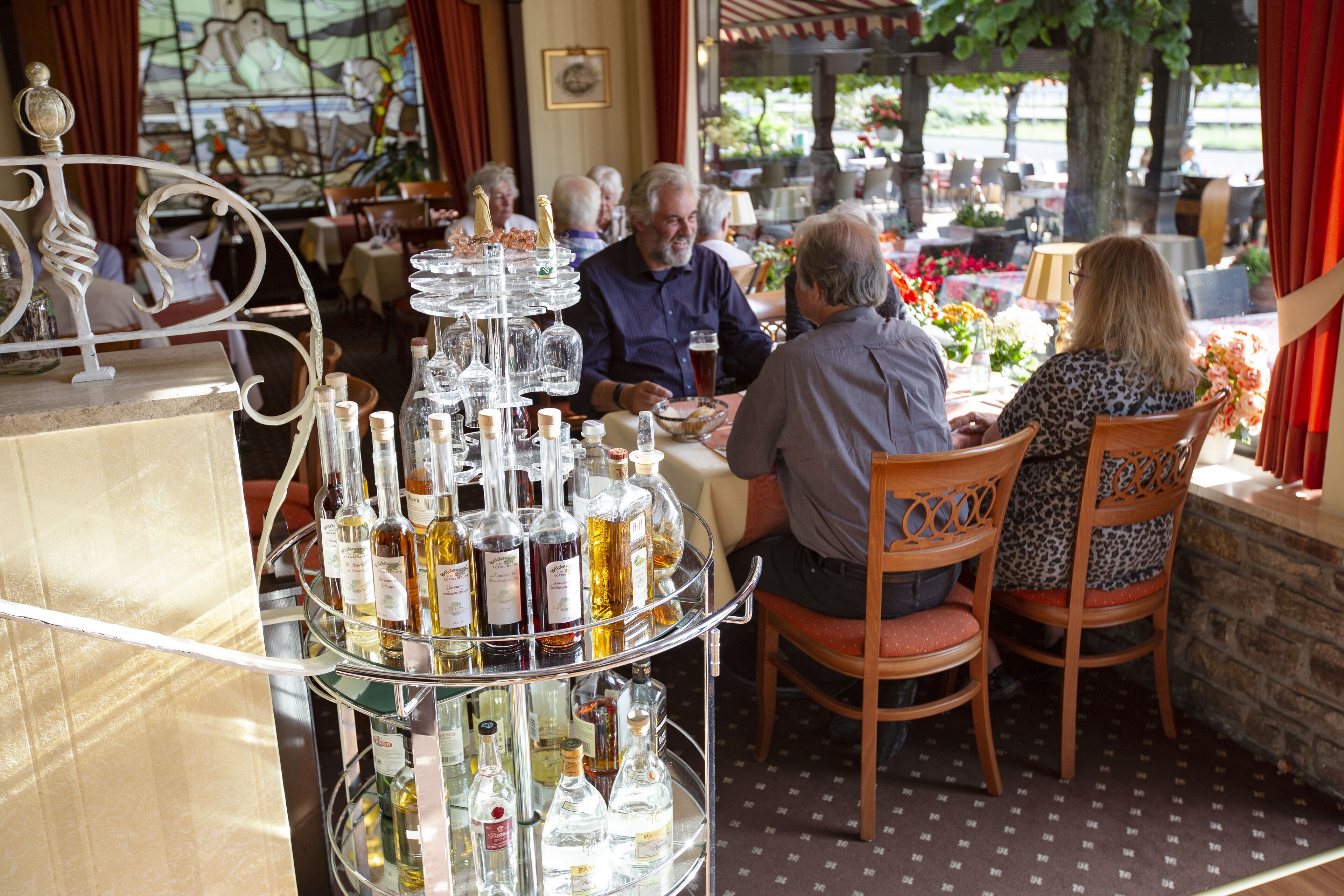 A restaurant with a wine display and patrons seated at tables.