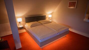 A neatly made bed with two pillows, a bedside table with a lamp, and a framed picture on the wall.