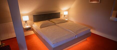 A neatly made bed with two pillows, a bedside table with a lamp, and a framed picture on the wall.