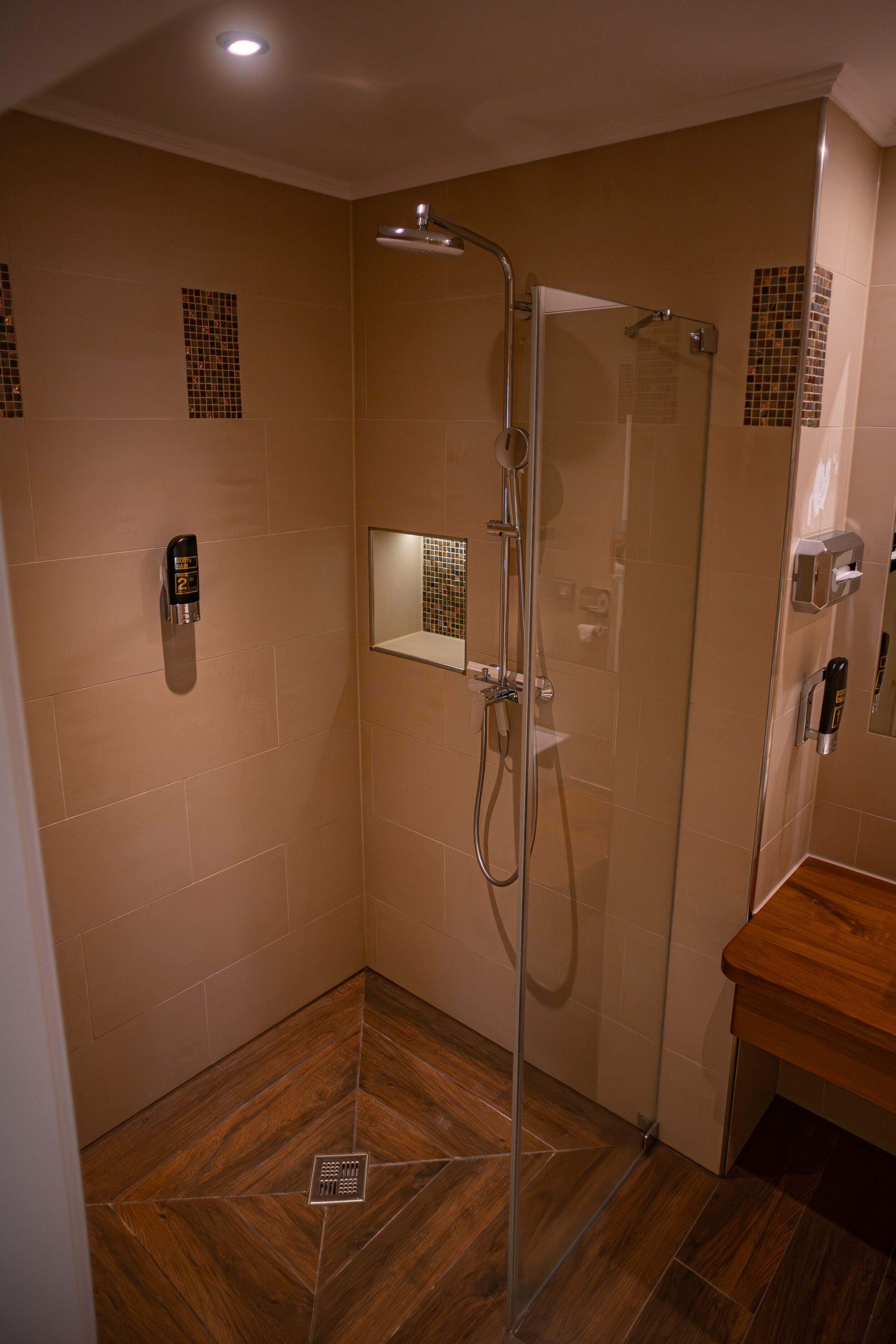 Een moderne douche met een glazen deur, een handdouche en een bedieningspaneel aan de muur.