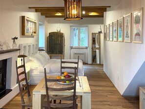 Une pièce chaleureuse avec une table à manger en bois, des chaises, un canapé blanc, une cheminée et des œuvres d’art encadrées accrochées aux murs.