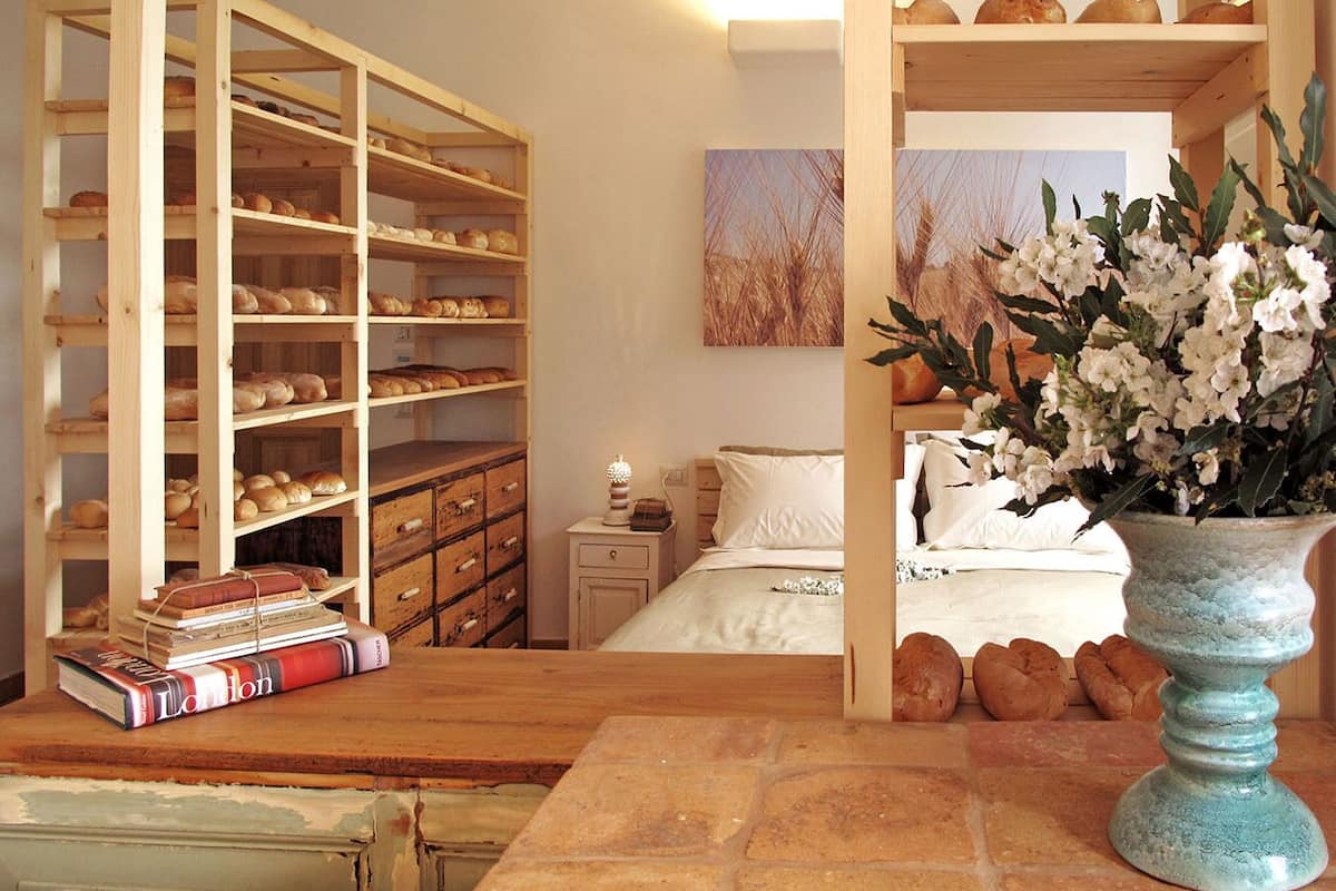 Ein Schlafzimmer mit einem Bett, einem Nachttisch, einem hölzernen Bücherregal und einer Vase mit Blumen.