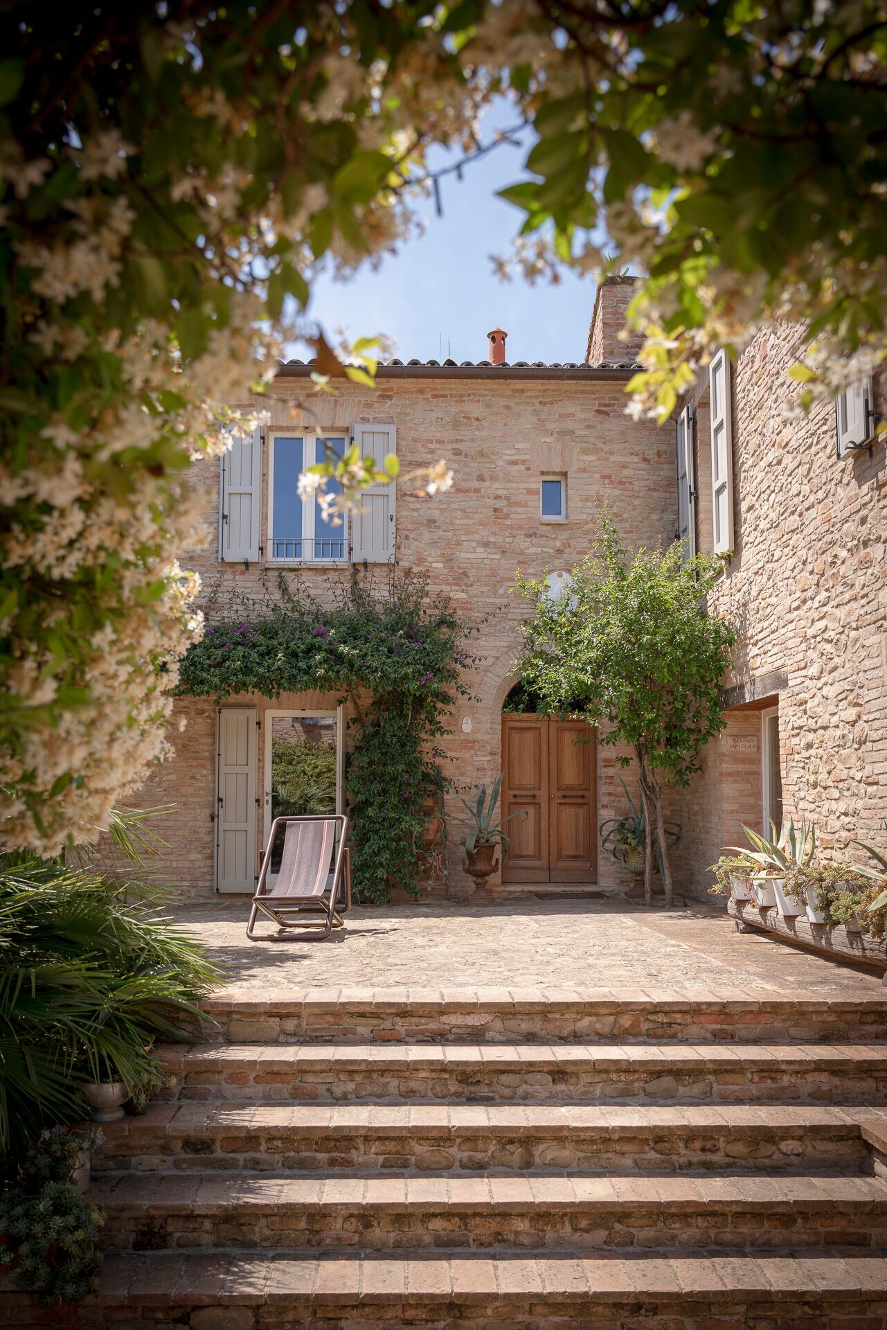 A stone building with a courtyard, steps leading up to the entrance, and a wooden door.