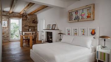 A bedroom with a bed, a fireplace, a dining area, and a stone wall.