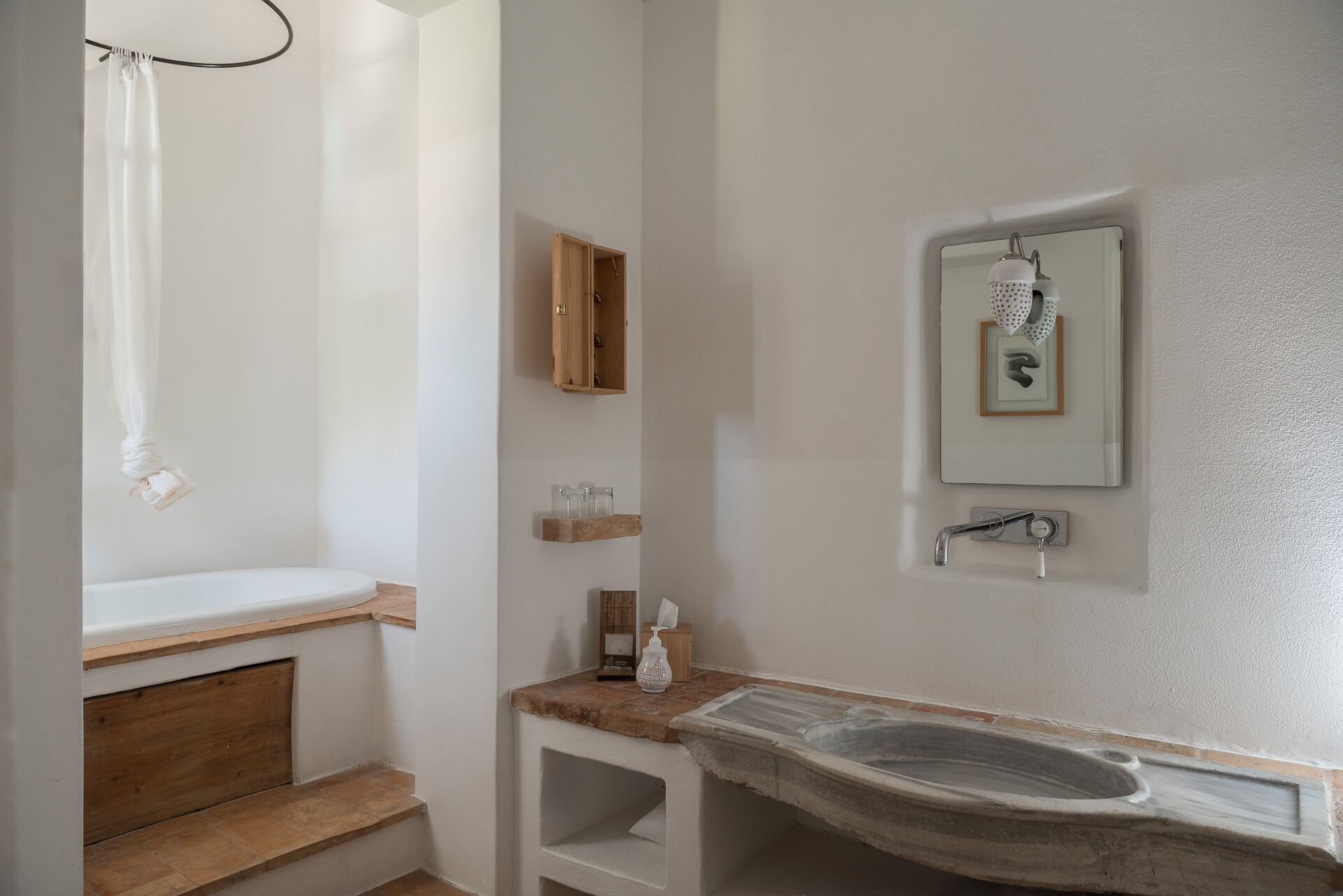 A bathroom with a wooden vanity, a freestanding bathtub, a shower curtain, a wooden cabinet, and a mirror with a framed picture.