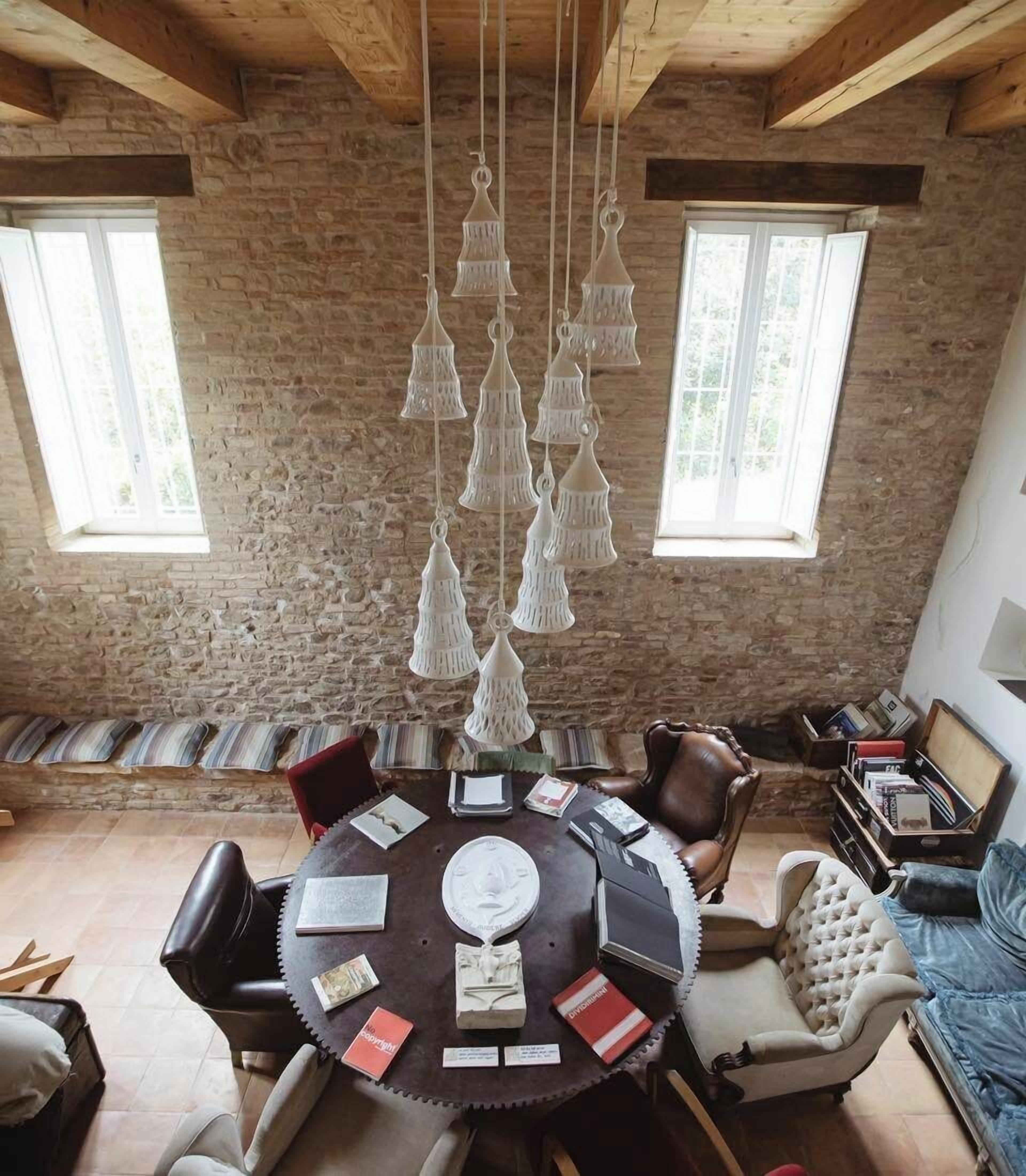 Un coin repas au style rustique, avec une table ronde, des chaises en cuir et un luminaire suspendu.