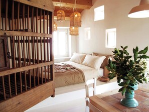 Une chambre à coucher avec un lit, une chaise en bois, une table et une plante en pot.