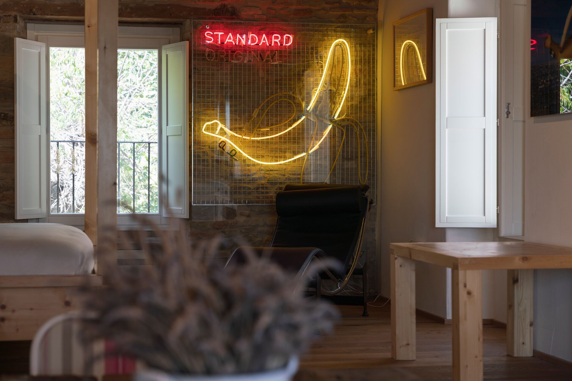 A room with a bed, a massage chair, a neon sign, and a window with a view.