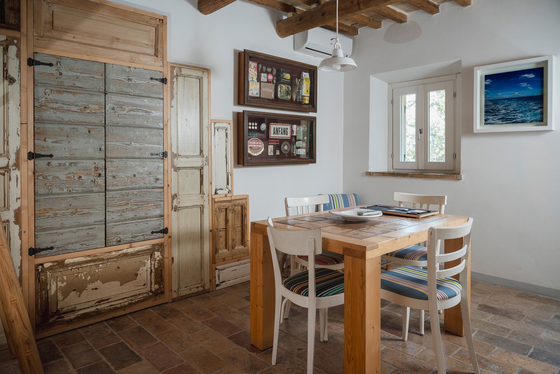 A dining area with a wooden table and chairs, a rustic door, and a framed picture on the wall.