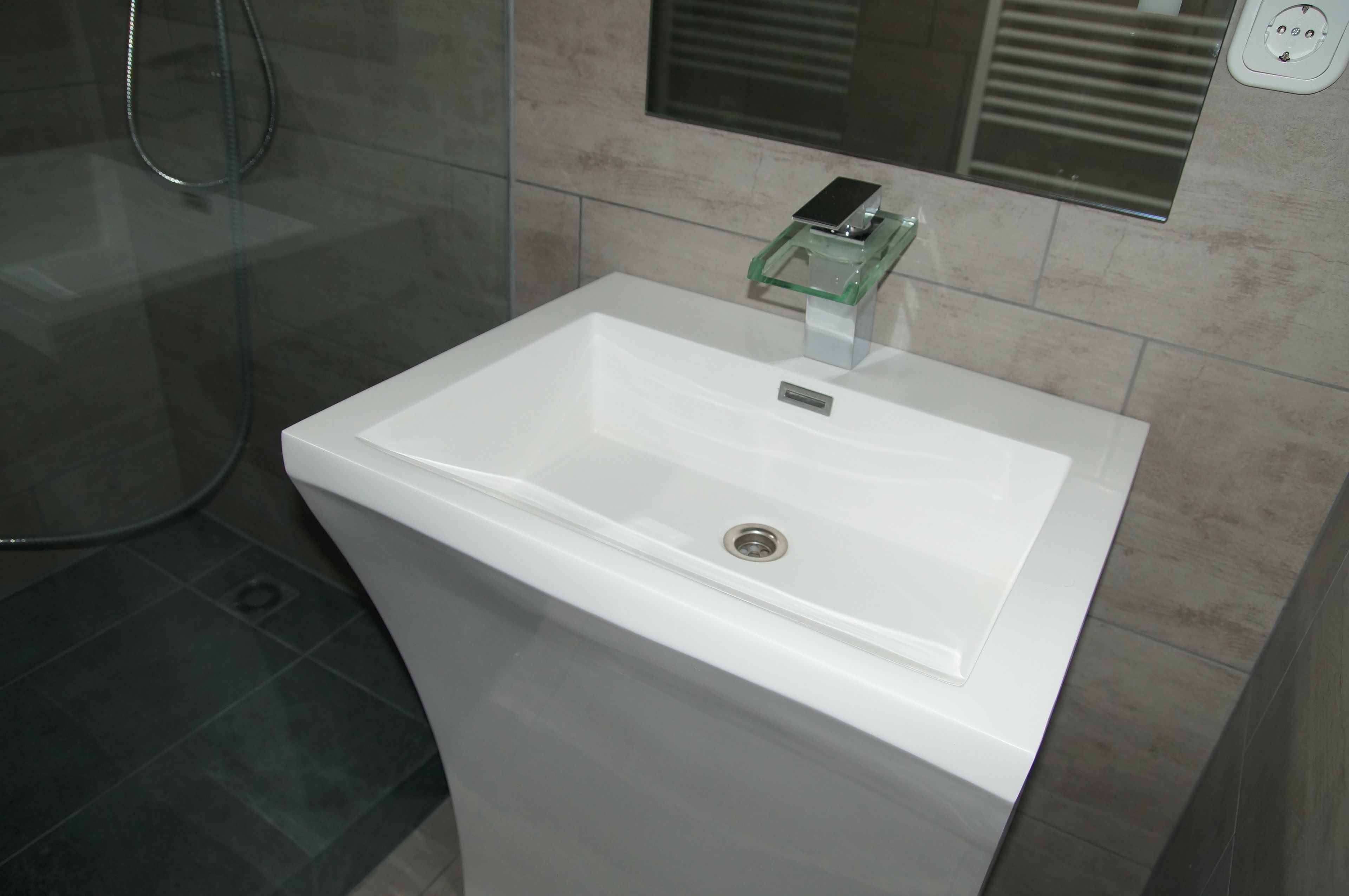 Un lavabo blanco con un jabonera de vidrio y un espejo encima.