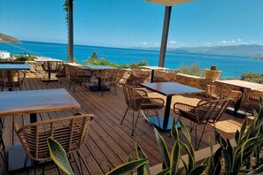 Een terras met rieten meubels en uitzicht op zee.