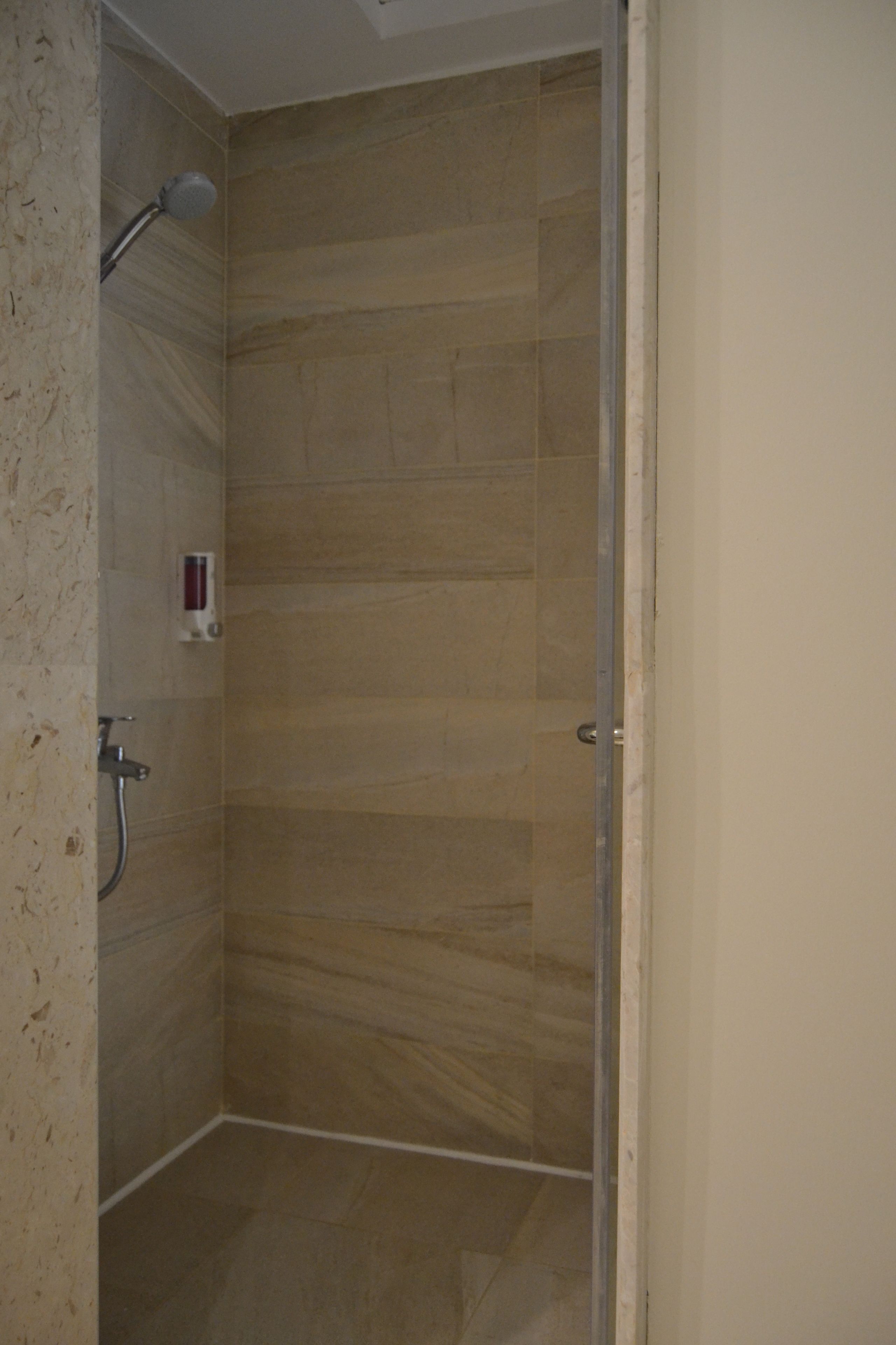 A shower with a glass door, tiled walls, and a handheld showerhead.
