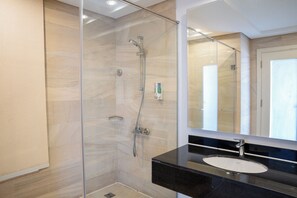 A modern bathroom with a glass-enclosed shower, a black countertop, and a large mirror. - Rivoli Suites (Hurghada)