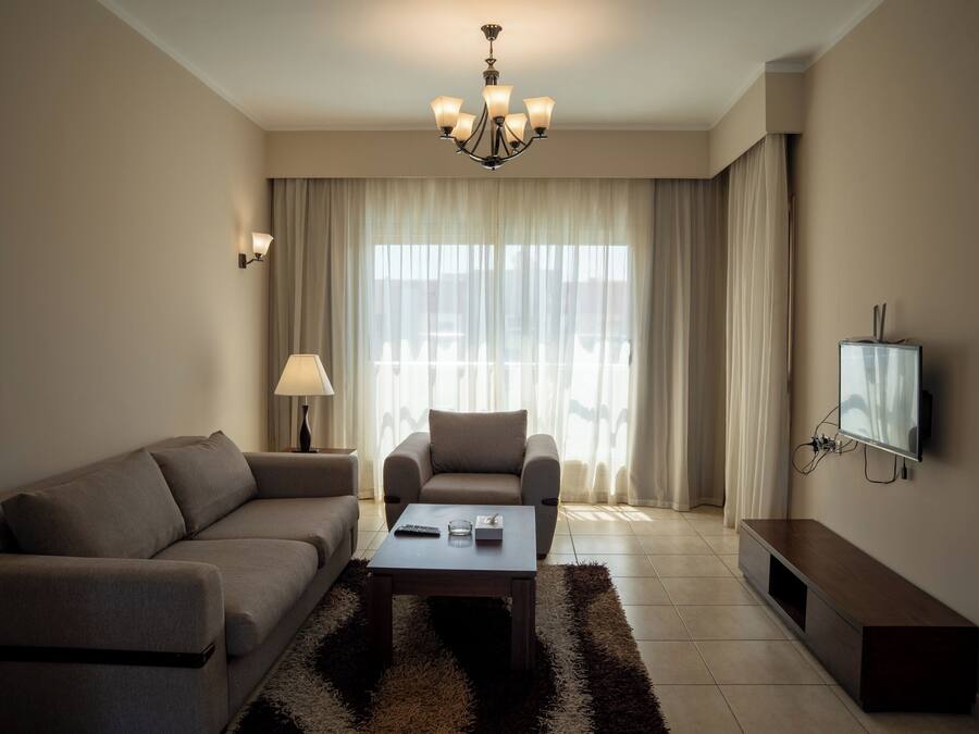 Ein modernes Wohnzimmer mit Sofa, Sessel, Couchtisch, Fernseher und einer Chandelier.