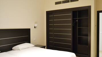 Un dormitorio con cama, mesita de noche, lámpara de pared y un armario amplio.
