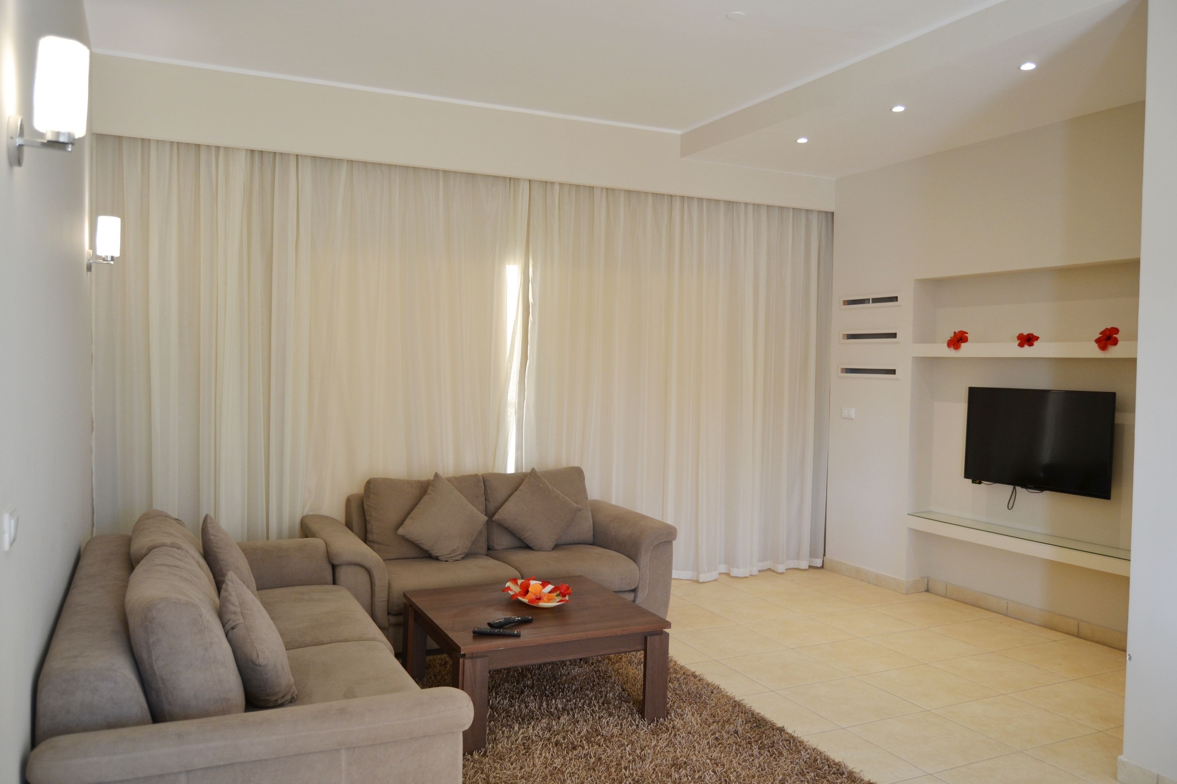 A living room with a sofa, a coffee table, and a flat-screen TV mounted on the wall.