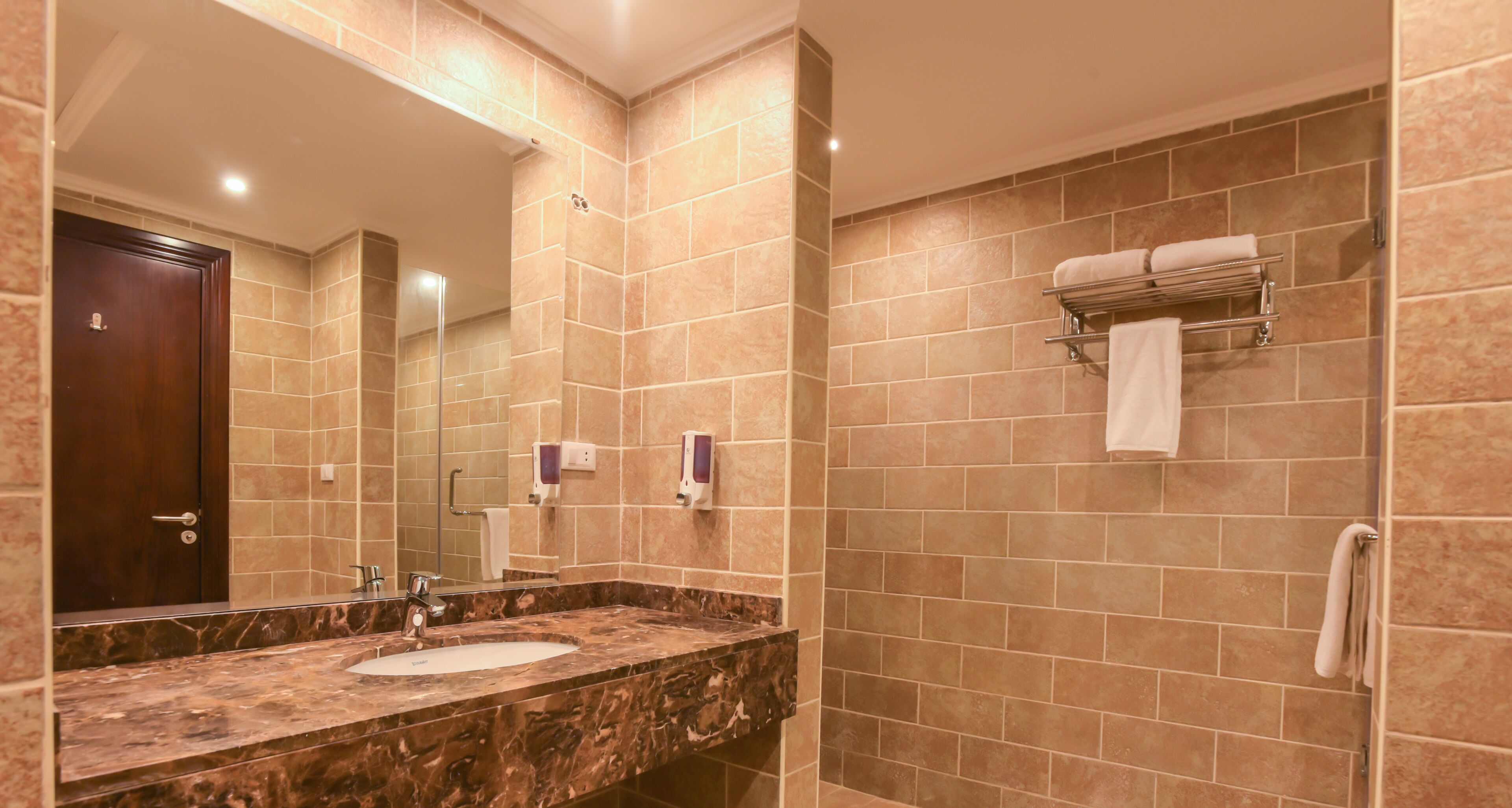 A bathroom with a marble sink, a large mirror, and a towel rack.
