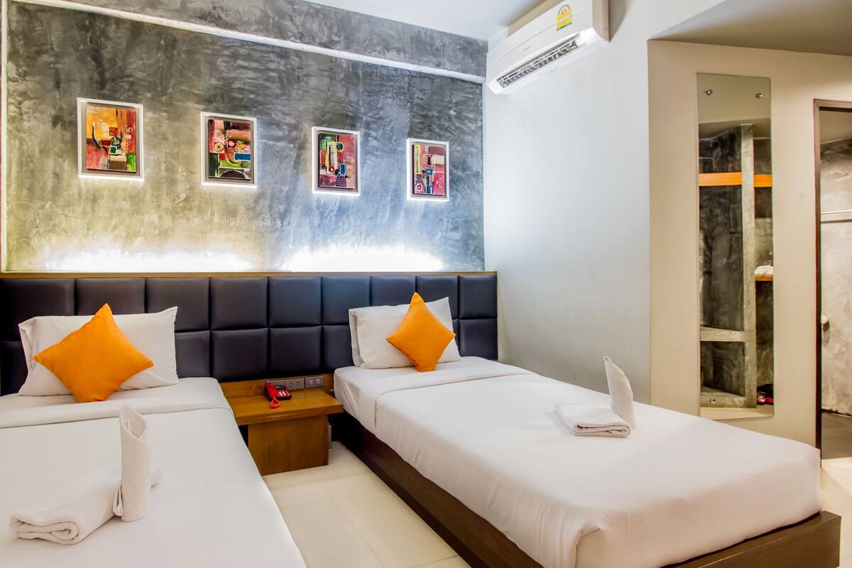 A hotel room with two beds, a marble wall, and four framed artworks.
