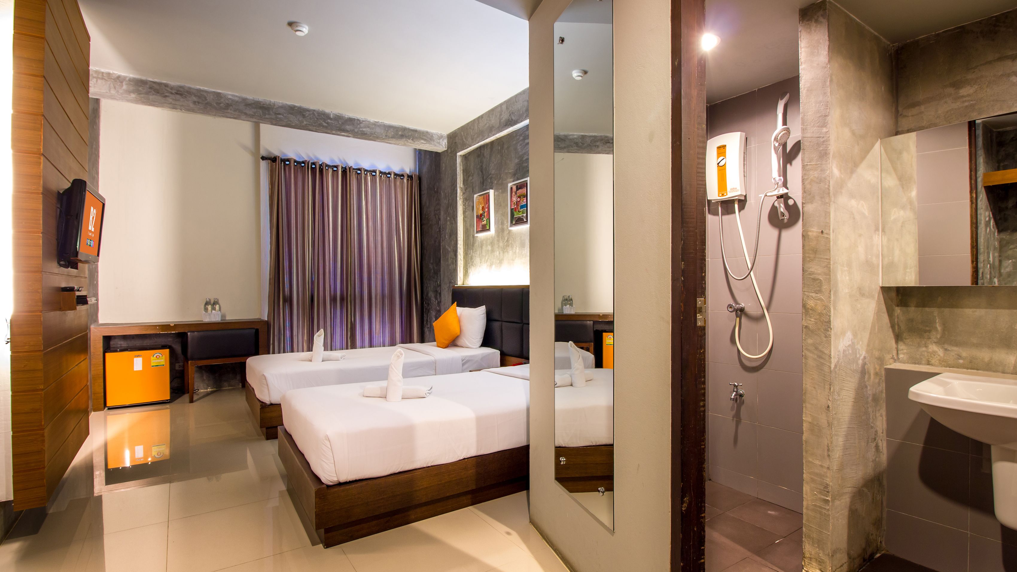 A hotel room with two beds, a shower, a sink, and a minibar.