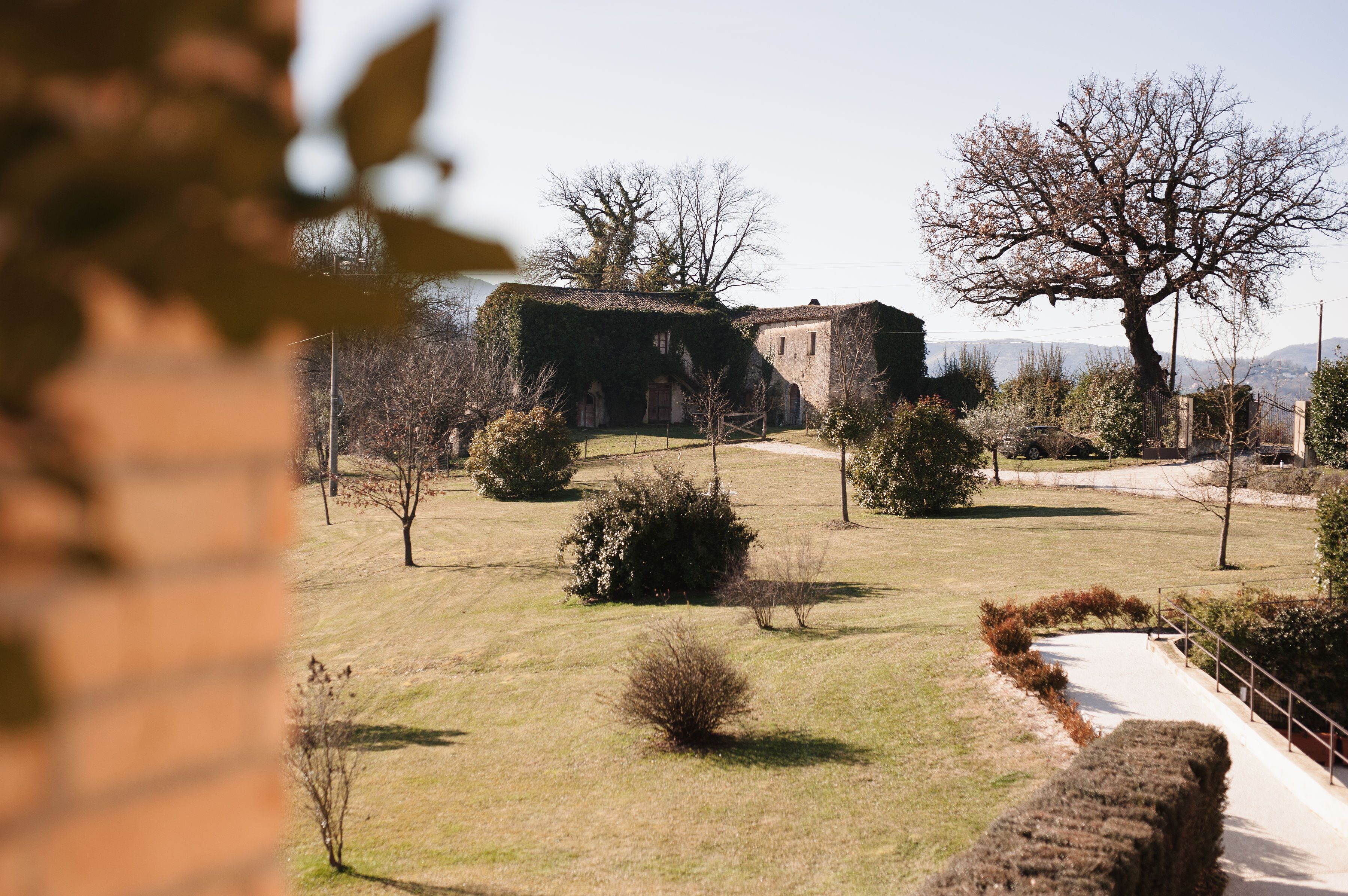 A historic building with a stone facade, surrounded by a well-maintained lawn and a few trees.