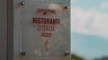 Un letrero con el texto 'Gambero Rosso Ristorante D'Italia 2023' y un símbolo de tenedor.