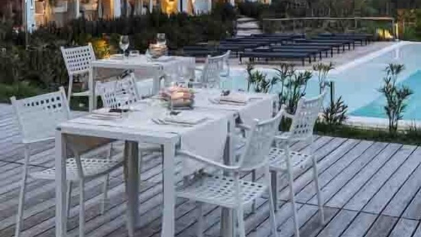 An outdoor dining area with white furniture and a pool, overlooking a mountainous landscape. - Relais Colle Buono (Alvito)