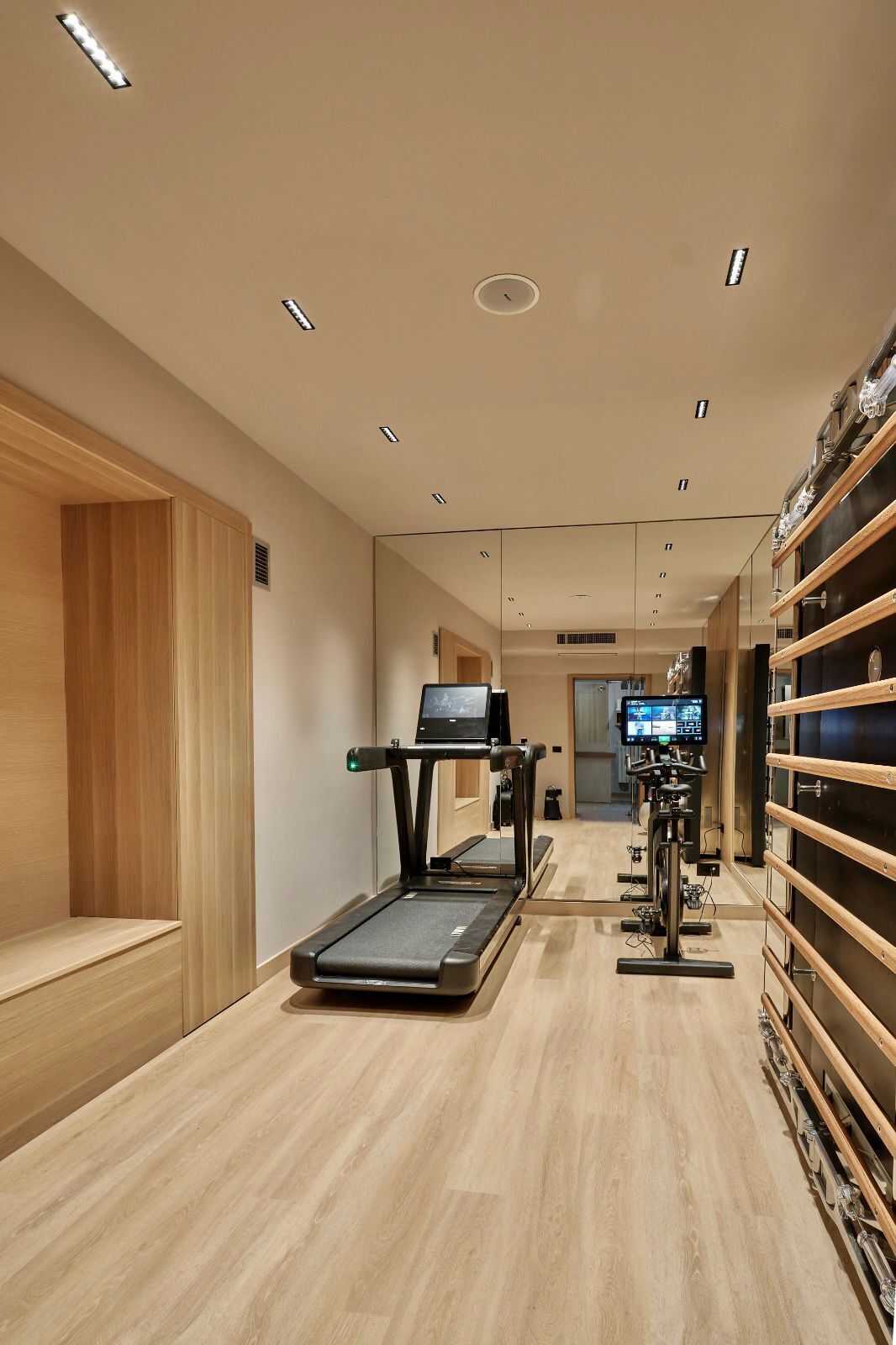 Un gimnasio moderno con cintas de correr, bicicletas estáticas y una pantalla de televisión.