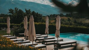 A poolside area with lounge chairs and umbrellas, overlooking a mountainous landscape. - Relais Colle Buono (Alvito)