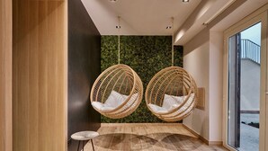 A modern interior with two wicker hanging chairs, a small round table, and a green textured wall. - Relais Colle Buono (Alvito)