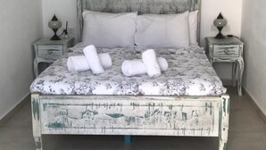 Un dormitorio con una cama, dos mesitas de noche, un cuadro y una araña.