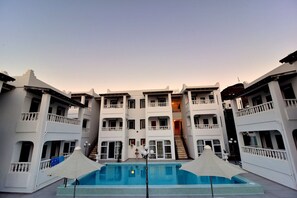 A multi-story hotel with a central pool area, balconies, and a staircase leading to an upper floor. - Bahama Art Hotel (Bodrum)
