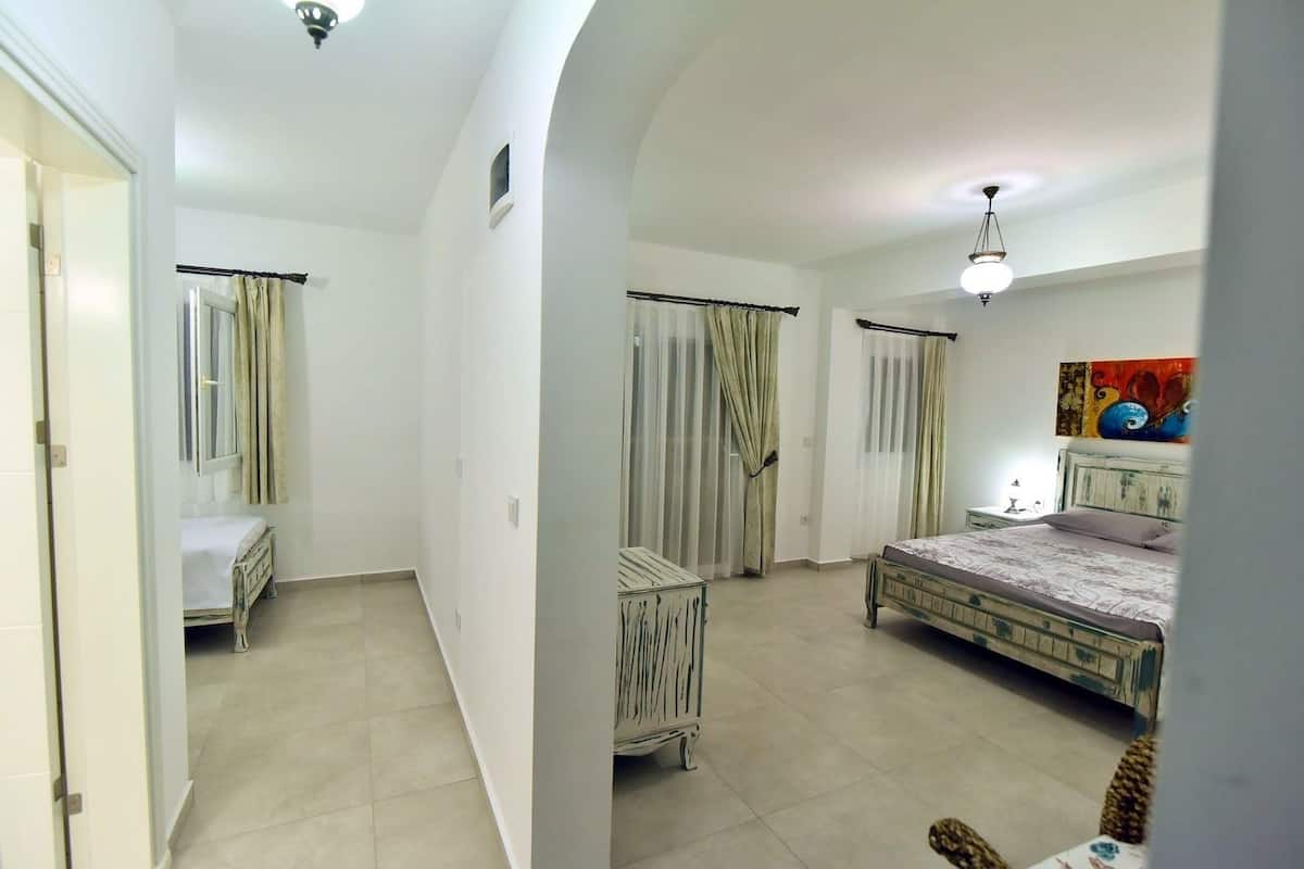 Un dormitorio con cama, mesita de noche, una silla y un cuadro en la pared.