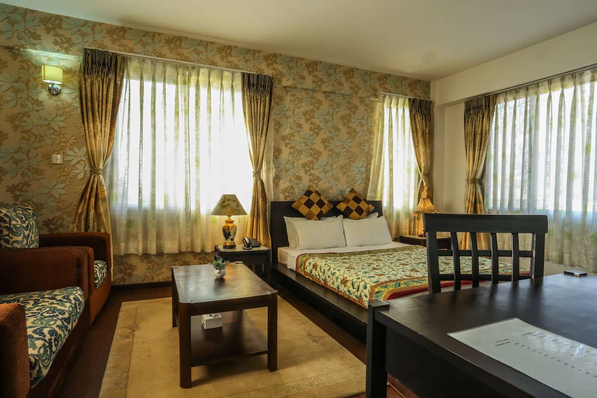 Una habitación de hotel con cama, sofá, mesa y cortinas.