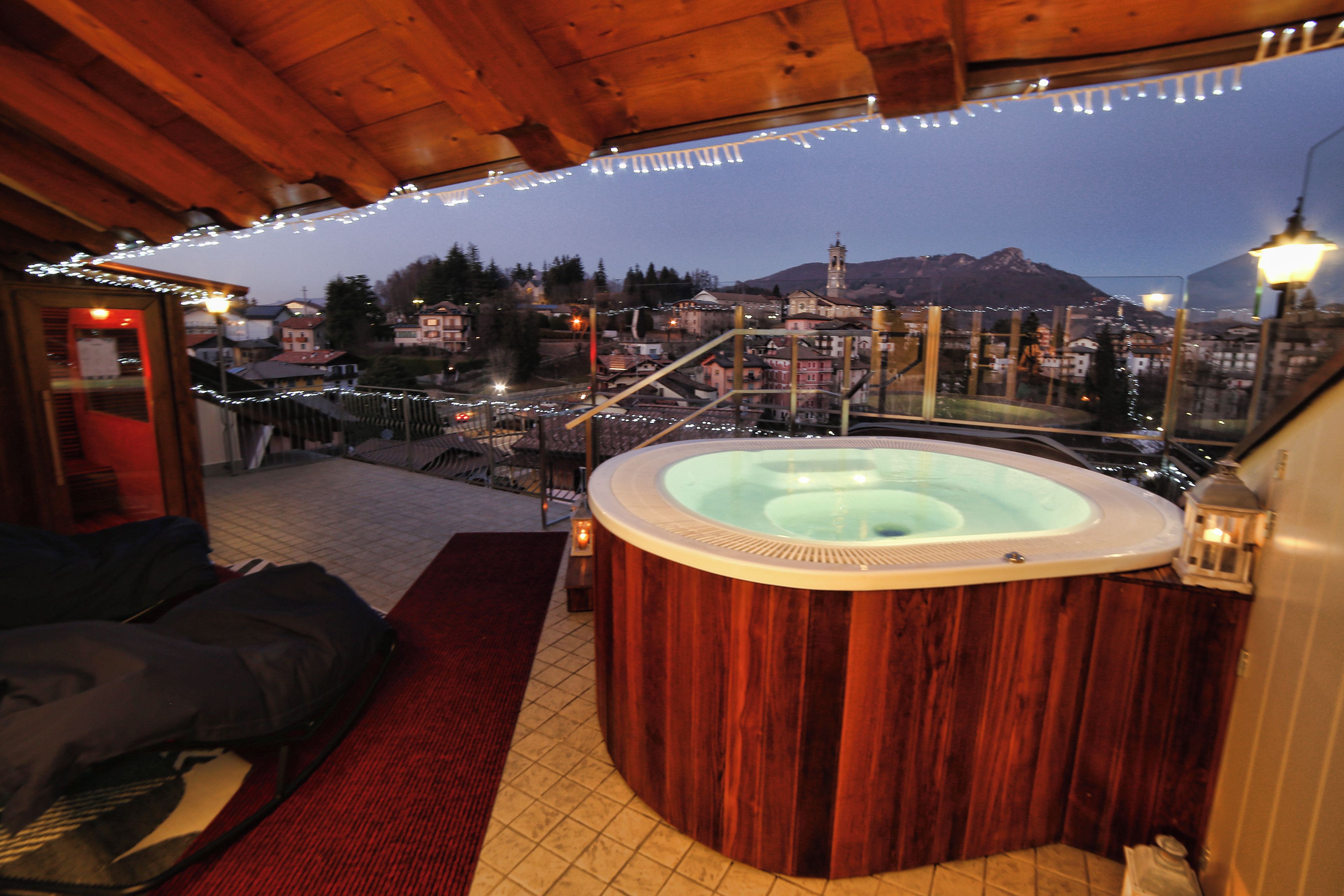 A hot tub in a wooden cabin with a view of a town and mountains.