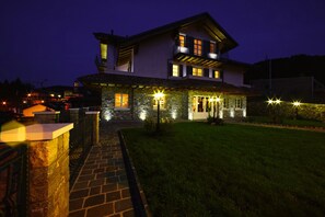 A two-story house with a stone facade, a balcony, and a well-lit entrance. - T'AMI Hotel Resort SPA (Selvino)