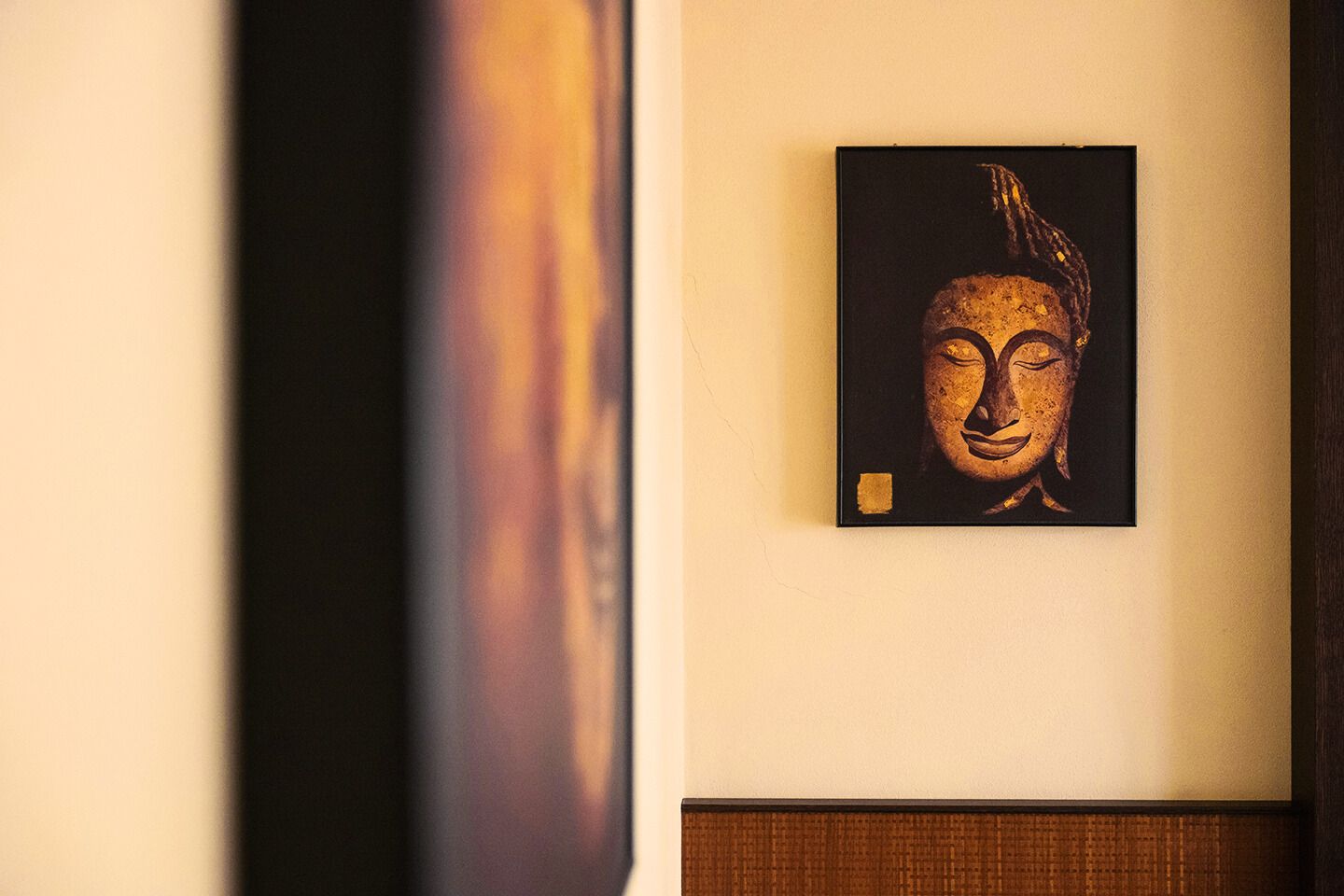 A framed artwork of a Buddha's head on a wall.