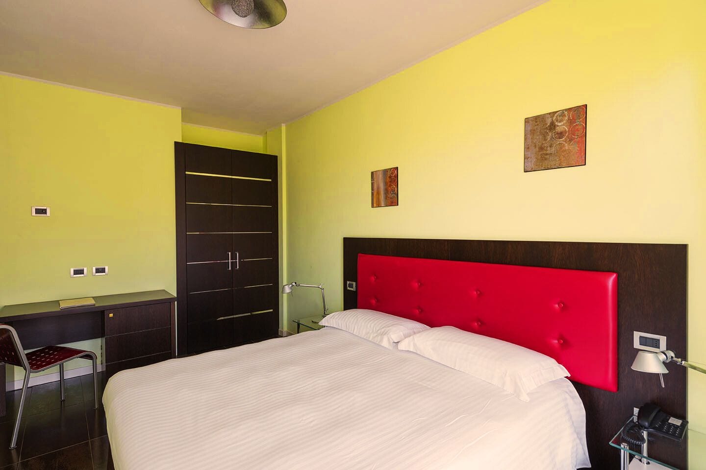 Une chambre d’hôtel comprenant un lit, un bureau, une chaise et une armoire.