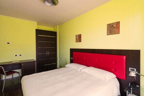 Una habitación de hotel con cama, escritorio, silla y armario.