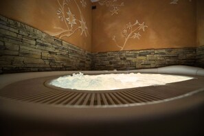 A hot tub with a stone wall and floral wall art. - T'AMI Hotel Resort SPA (Selvino)