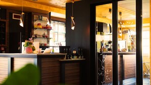 A modern bar area with wooden accents, hanging pendant lights, and a glass partition. - T'AMI Hotel Resort SPA (Selvino)