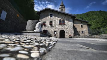Un edificio de piedra con un campanario, una estatua al frente y un camino adoquinado que lleva a la entrada.