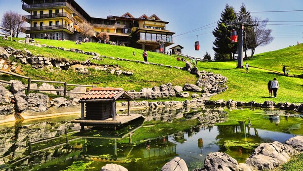 A hotel with a large building, a pond, and a small wooden structure. - T'AMI Hotel Resort SPA (Selvino)