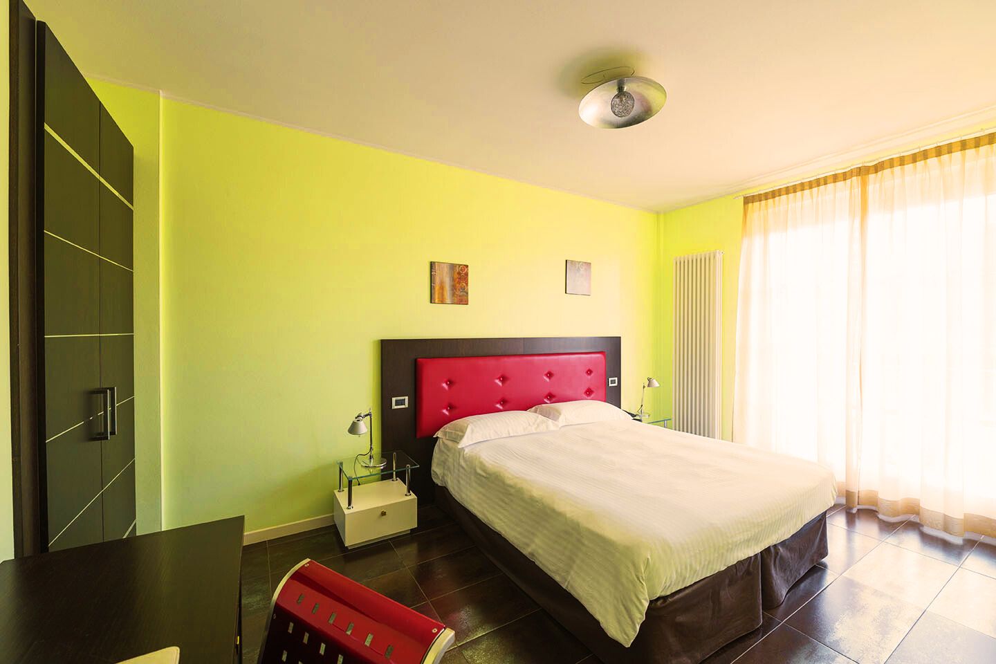 Ein Hotelzimmer mit Bett, Nachttisch, Schreibtisch und Stuhl.