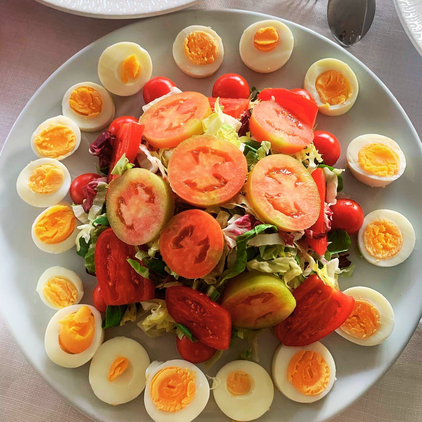 En tallrik med sallad, tomater, salladsblad och hårdkokta ägg.