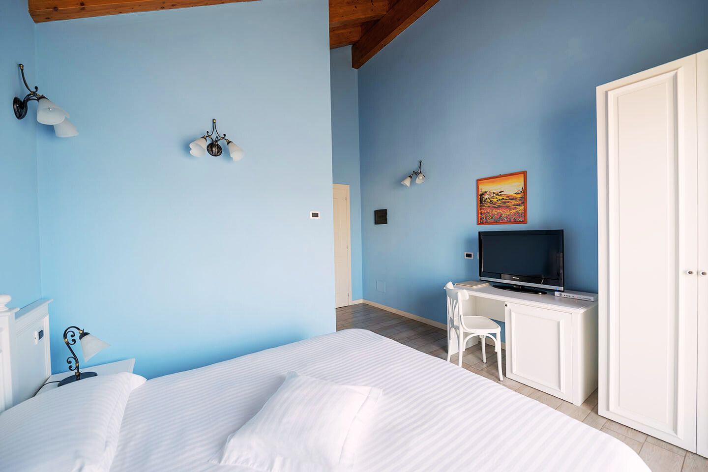 Un dormitorio con una cama, un escritorio con televisor, una silla y un armario.