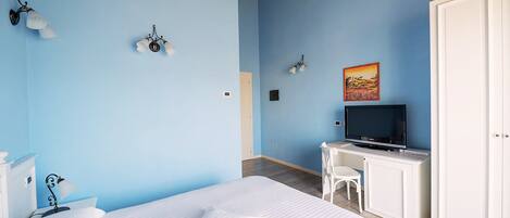 Un dormitorio con una cama, un escritorio con televisor, una silla y un armario.