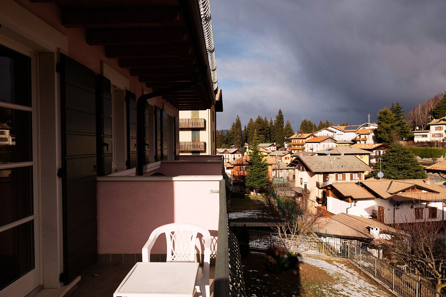 A balcony with a view of a residential area, including houses and trees.