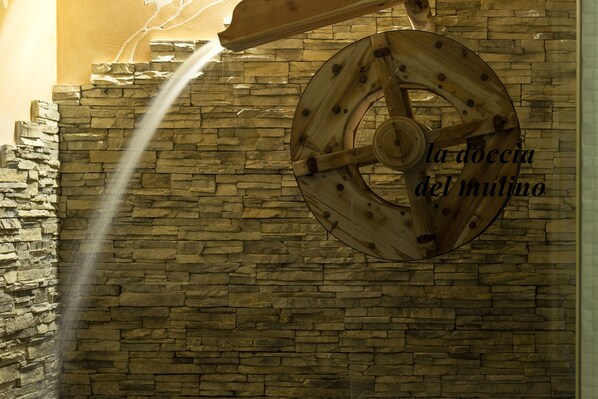 A stone wall with a wooden wheel structure. - T'AMI Hotel Resort SPA (Selvino)