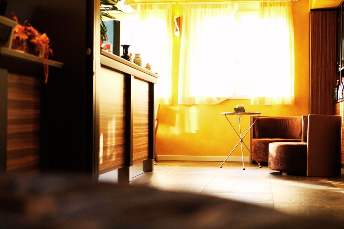 A room with a sofa, a small table, and a window with curtains.